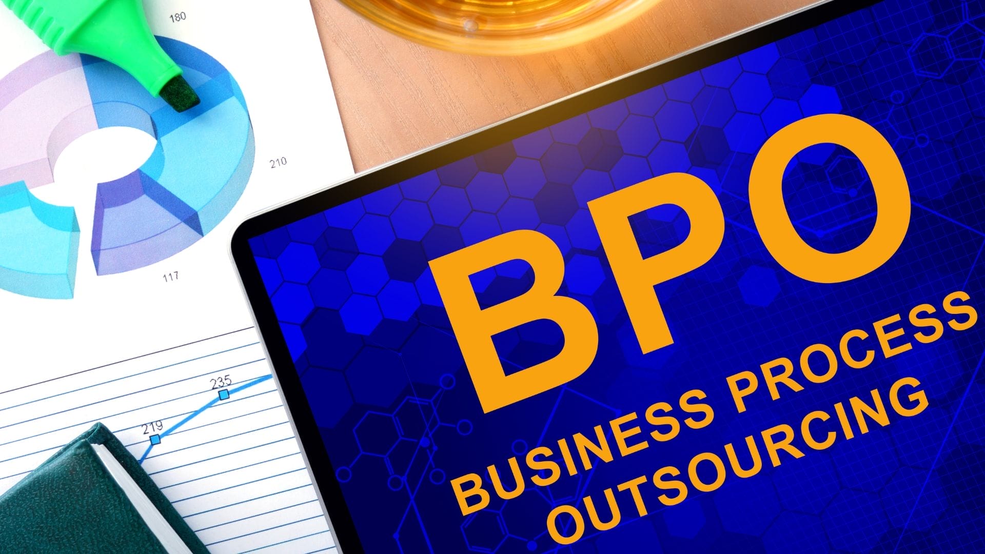 A tablet displaying "BPO Business Process Outsourcing" next to a chart, a notebook, and a highlighter.