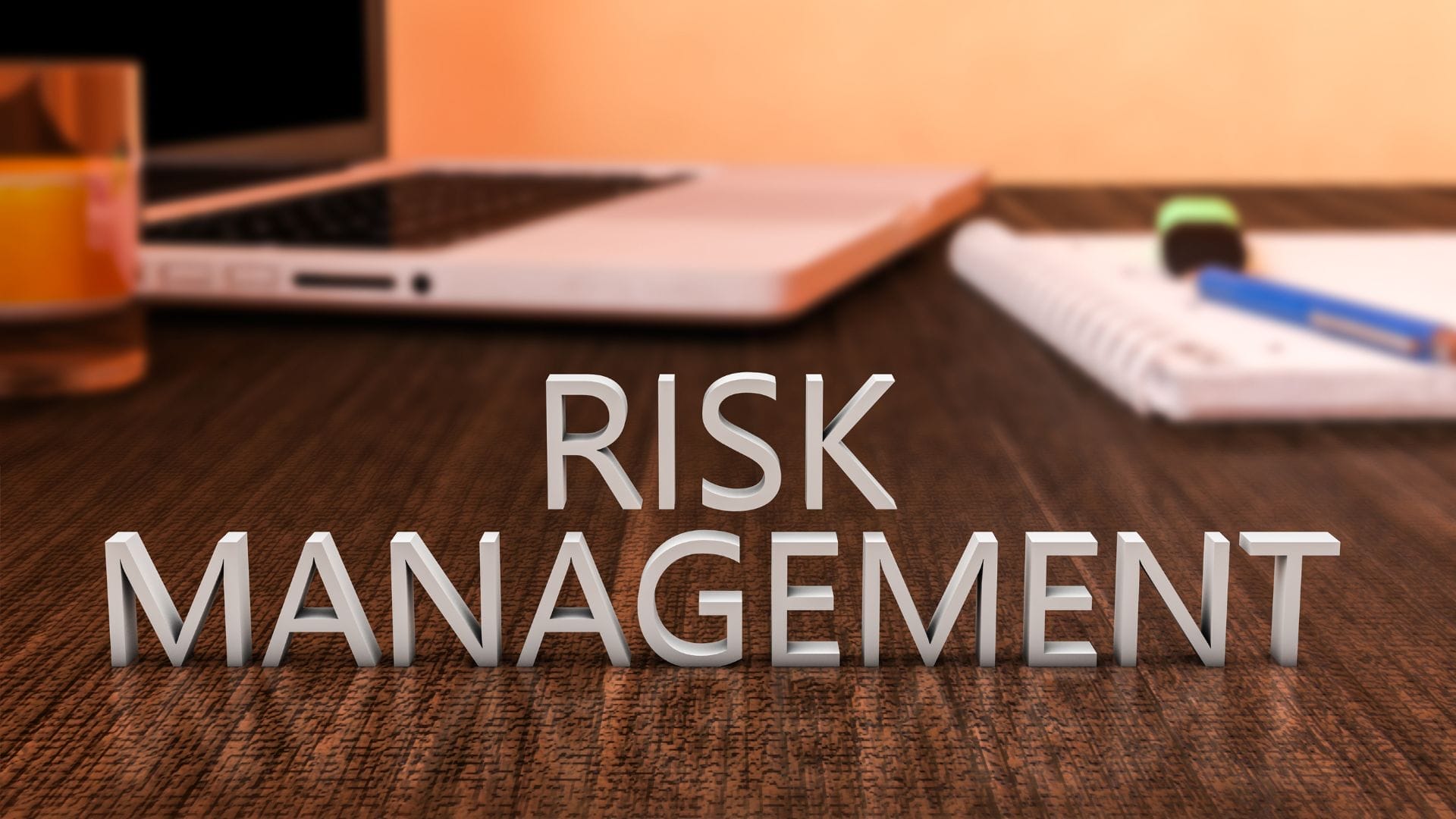 A workspace with a laptop, pen, and coffee, illustrating the theme of risk management and strategic planning.