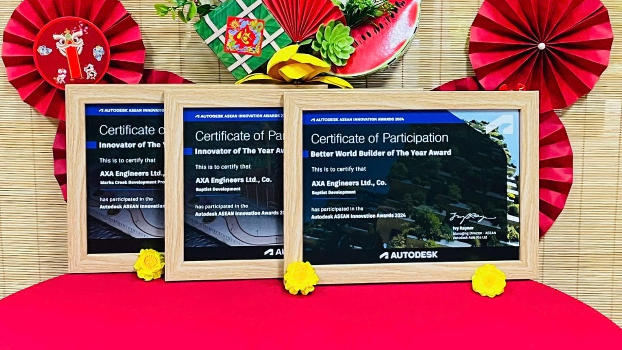 Three framed certificates from the Autodesk Innovation Awards 2023, including an Innovator of the Year accolade, are displayed on a red surface with decorative paper fans and a tray of festive ornaments in the background. AXA Engineers proudly celebrates their recognition amidst this vibrant setting.
