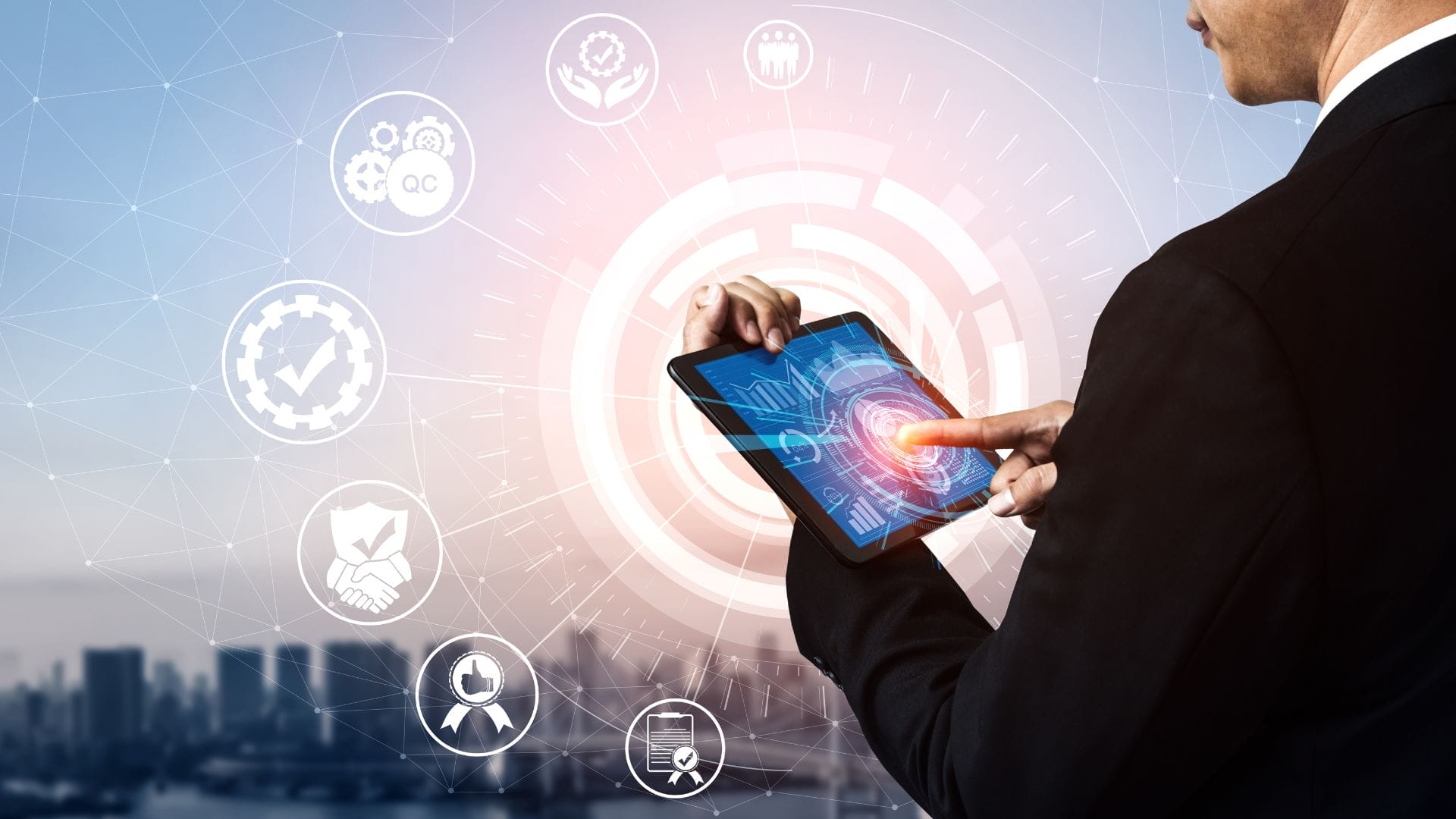 A person in a suit uses a tablet with a glowing interface, where holographic icons representing quality control KPIs, teamwork, settings, and other business concepts float around. In the blurred background, a city skyline is visible.
