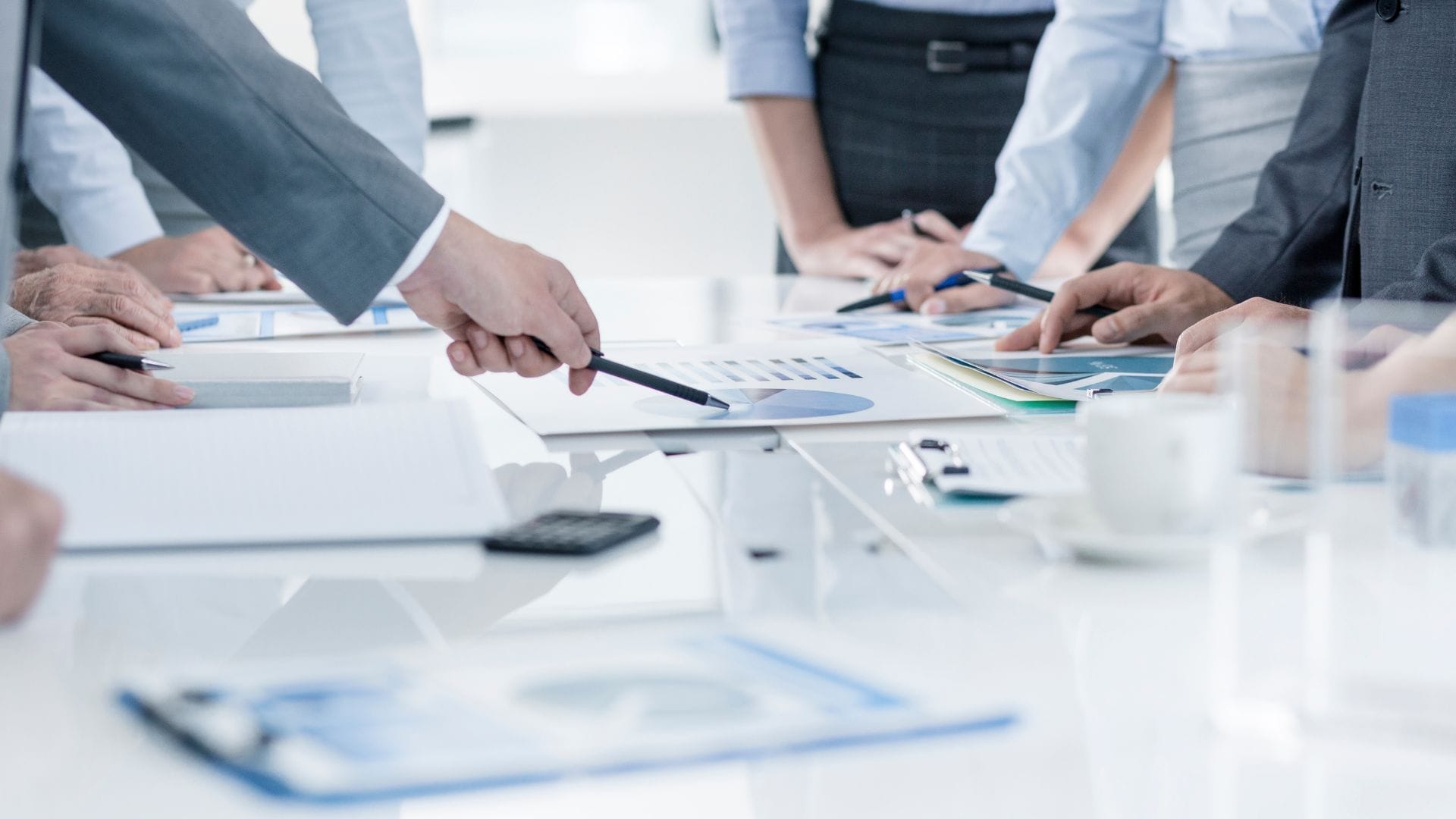 Civil Engineering Outsourcing A team of business professionals gathers around a conference table, closely reviewing documents and charts as they discuss civil engineering outsourcing. Their hands point to various graphs and papers while they collaboratively analyze potential risks associated with outsourcing civil engineering services during the meeting.