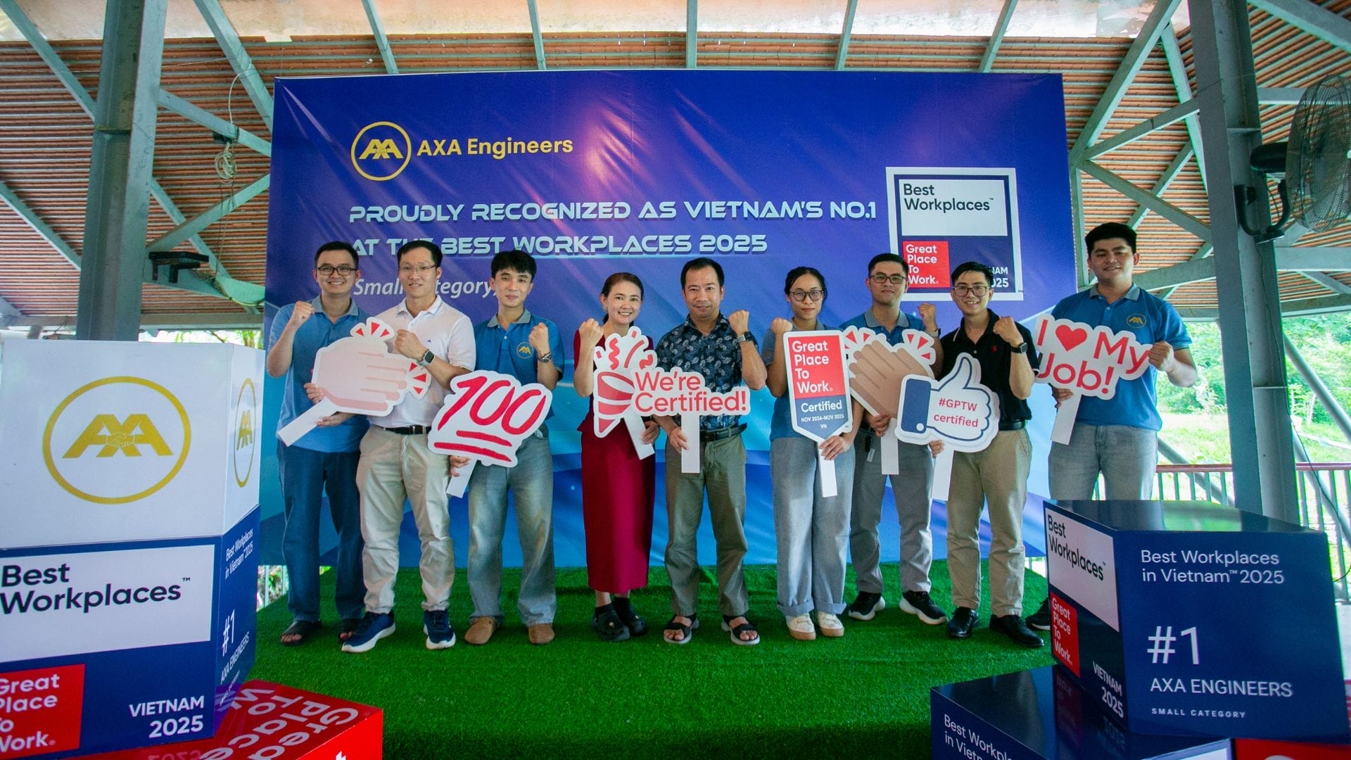 Civil Engineering Outsourcing A group of people stand on a stage holding signs with positive messages like We’re Certified! and I love my job, celebrating meaningful moments at the AXA Engineers event for Vietnam’s #1 Best Workplace 2025 during the KELTIC–AXA Engineers Trip 2025. The event highlighted the company’s outstanding achievements in civil engineering outsourcing and its commitment to fostering employee happiness and recognition.