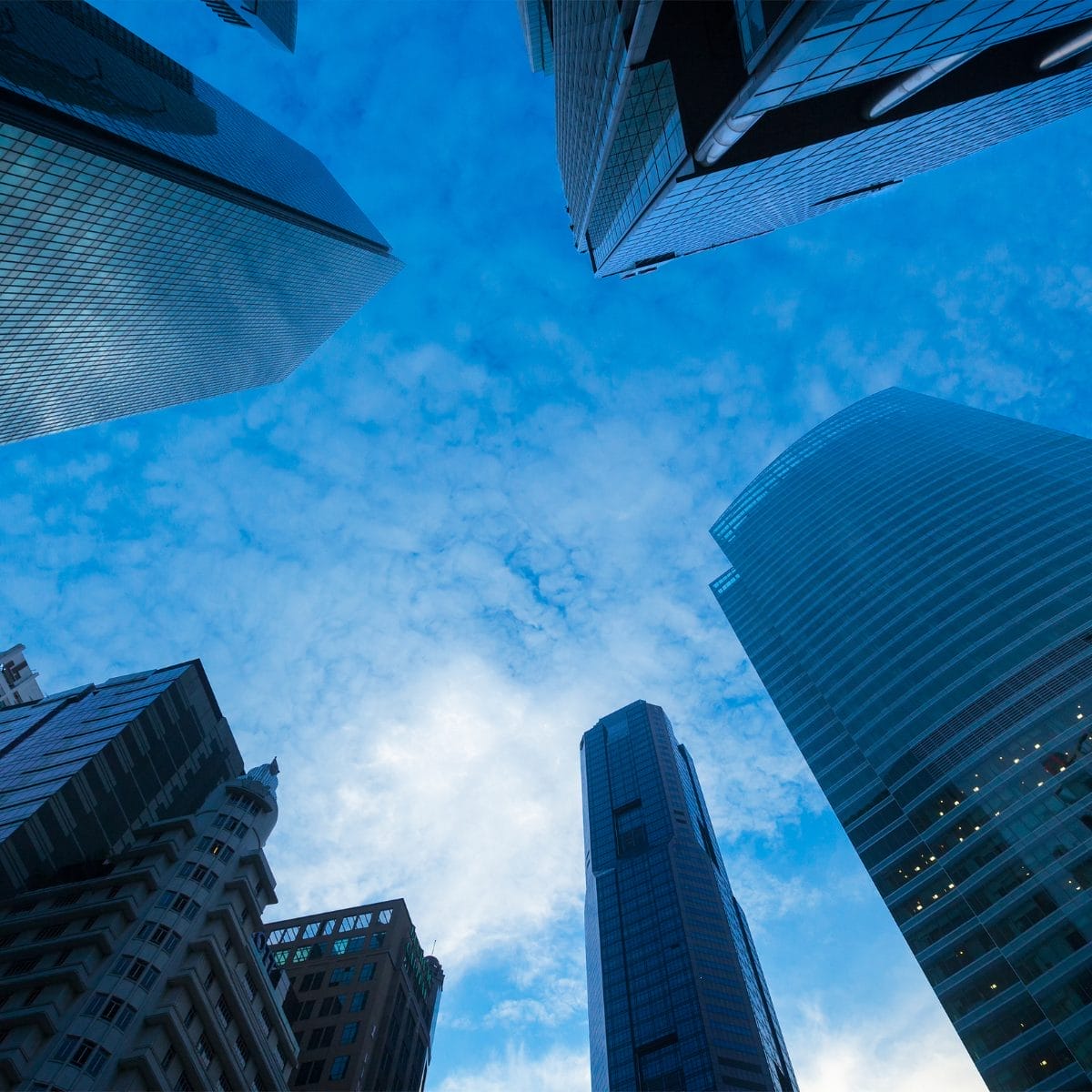 Civil Engineering Outsourcing Looking up at sleek skyscrapers and historic buildings, a clear blue sky frames the scene, reflecting civil engineering outsourcing.