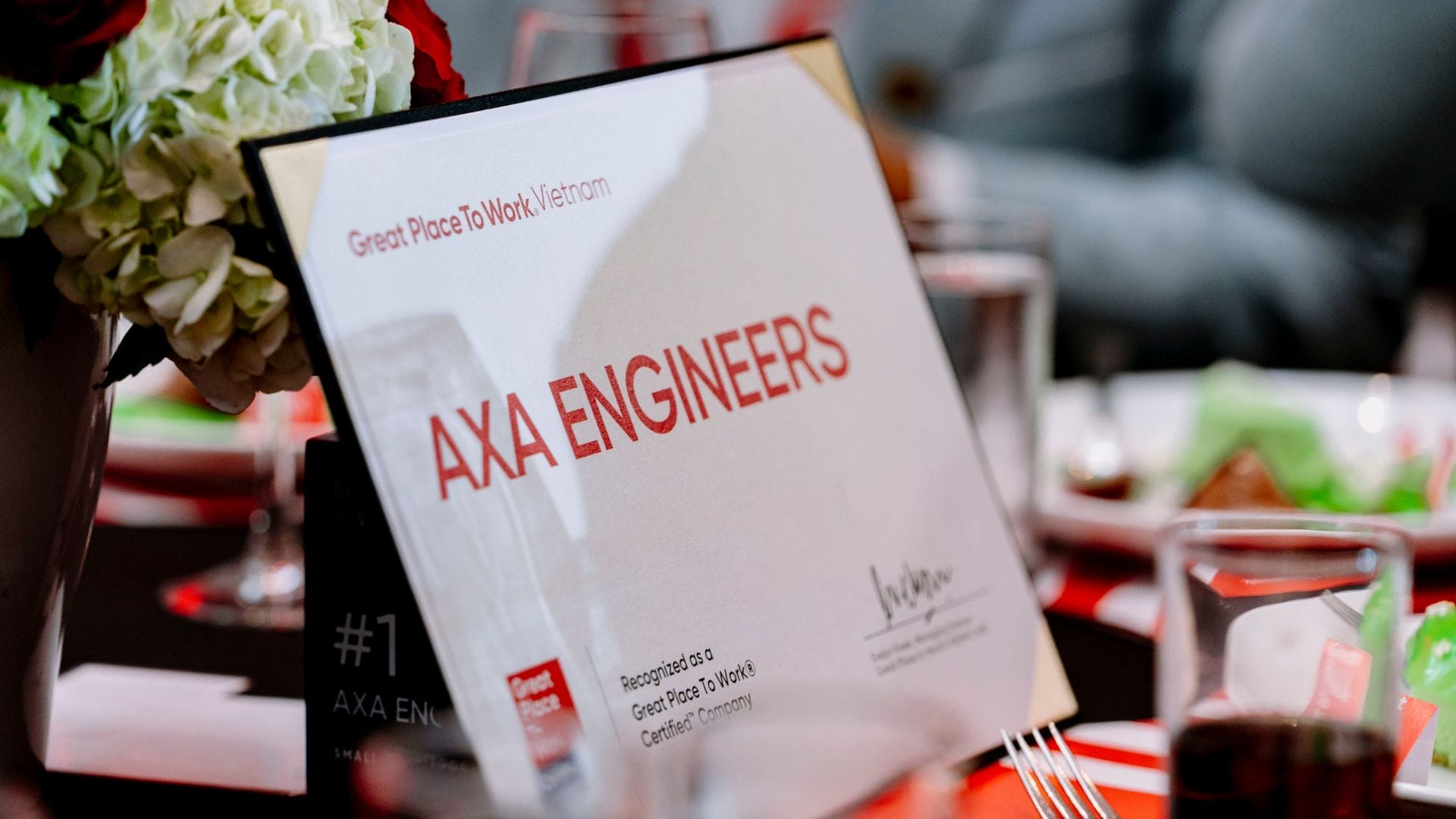 Civil Engineering Outsourcing A certificate featuring AXA ENGINEERS, known for civil engineering outsourcing, sits on a formal table with flowers and glasses.