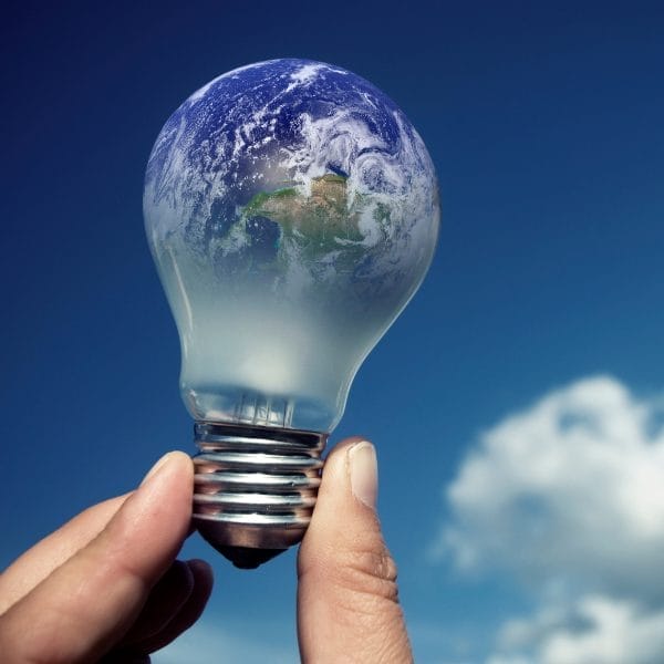 Civil Engineering Outsourcing A hand holds a lightbulb with Earth inside it against a blue sky, symbolizing global civil engineering outsourcing solutions.