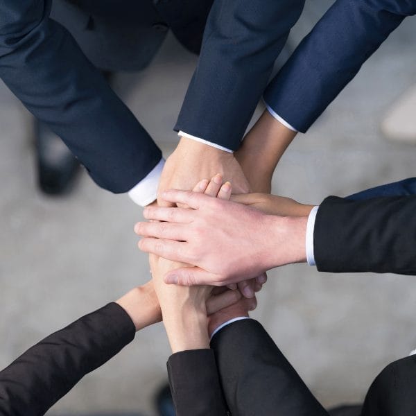 Civil Engineering Outsourcing Five professionals join hands in unity, symbolizing teamwork and the collaborative spirit of civil engineering outsourcing, top view.