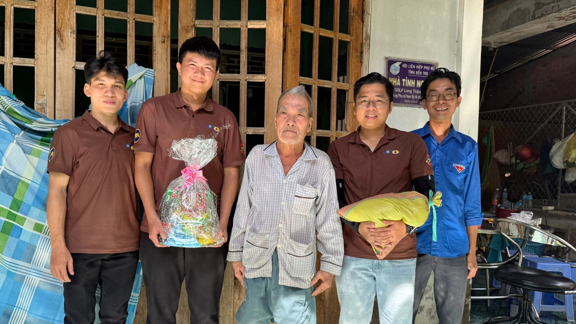Civil Engineering Outsourcing Five men, including civil engineering outsourcing volunteers from AXA Engineers, stand outside, holding a food package and rice bag.