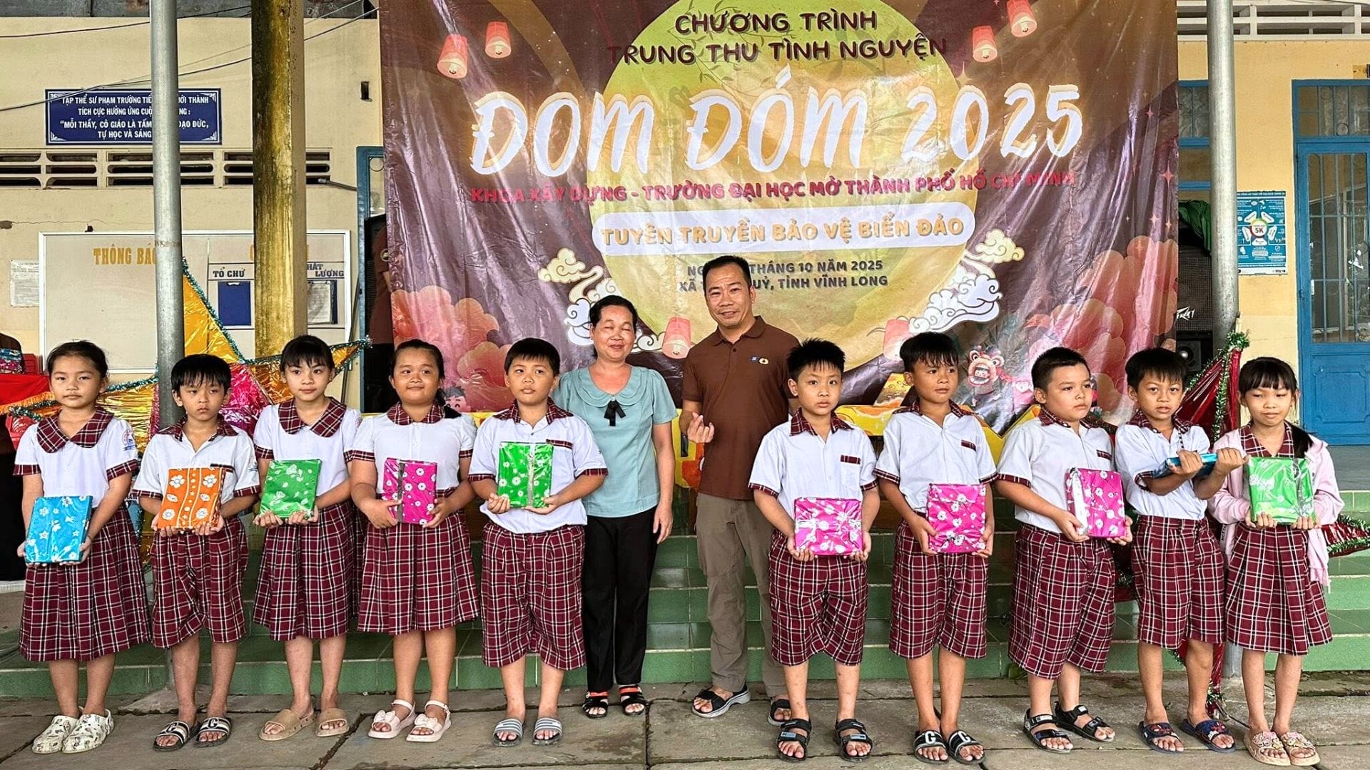 Civil Engineering Outsourcing Schoolchildren in uniform hold gift bags, standing with AXA Engineers' civil engineering outsourcing volunteers at the 2025 event.