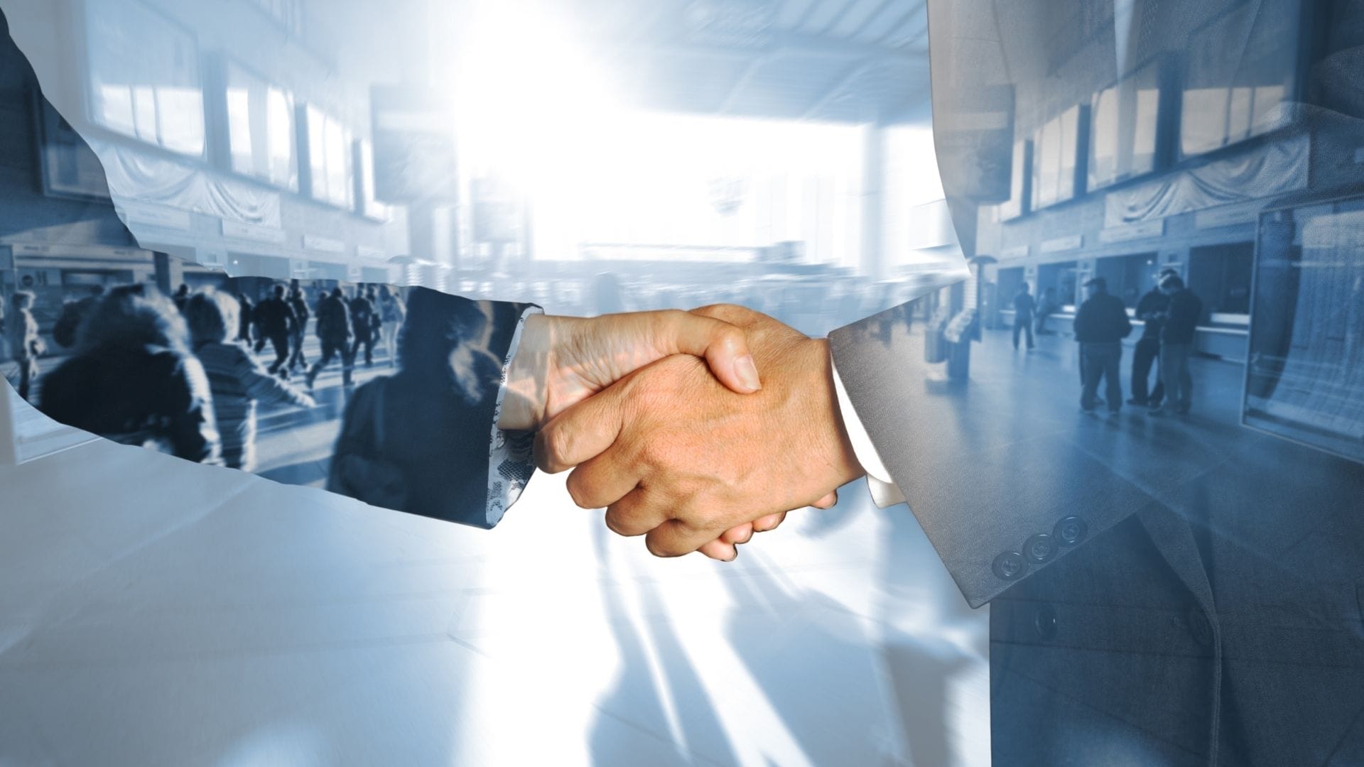 Civil Engineering Outsourcing Two people in suits shake hands in a busy indoor space, illustrating a civil engineering outsourcing agreement amid passing crowds.