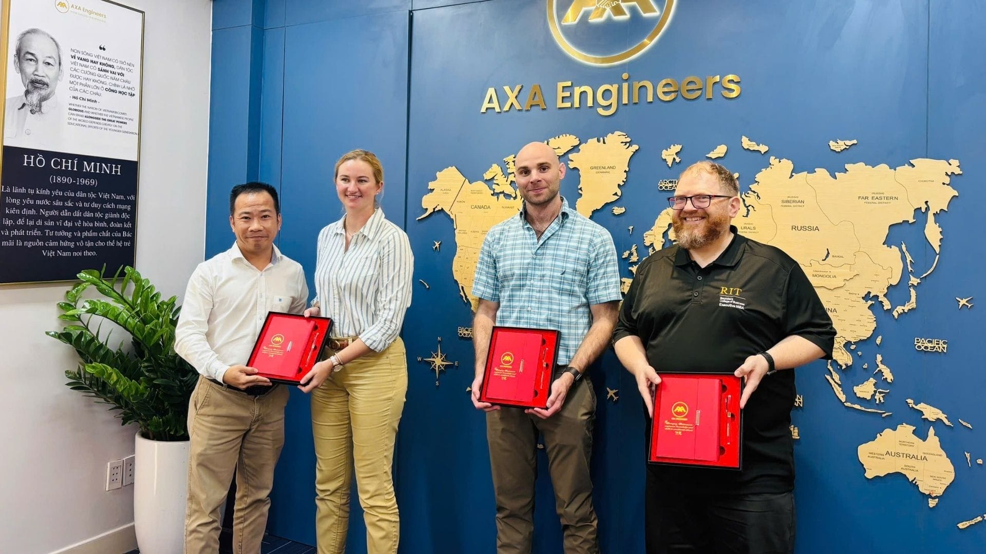 Civil Engineering Outsourcing Four people at AXA Engineers, a civil engineering outsourcing firm, hold red award folders before a blue wall with world map and logos.