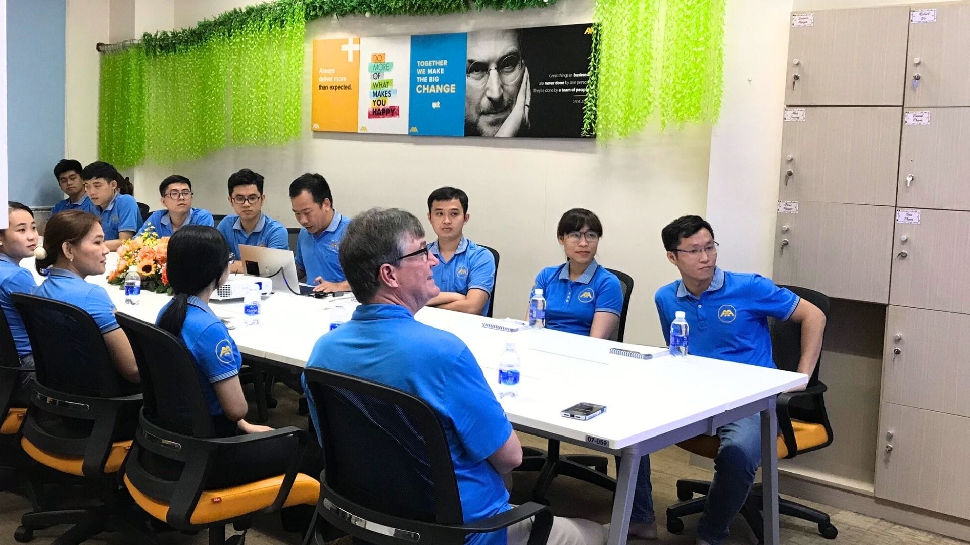 Civil Engineering Outsourcing A civil engineering outsourcing team in matching blue shirts sits at a conference table, listening during Partners' Visits in an office.