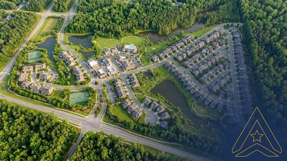 Civil Engineering Outsourcing Aerial view of Parkside Village Town, displaying well-planned homes, greenery, lakes, courts, pool, roads—built via civil engineering outsourcing. Gold geometric logo bottom right.